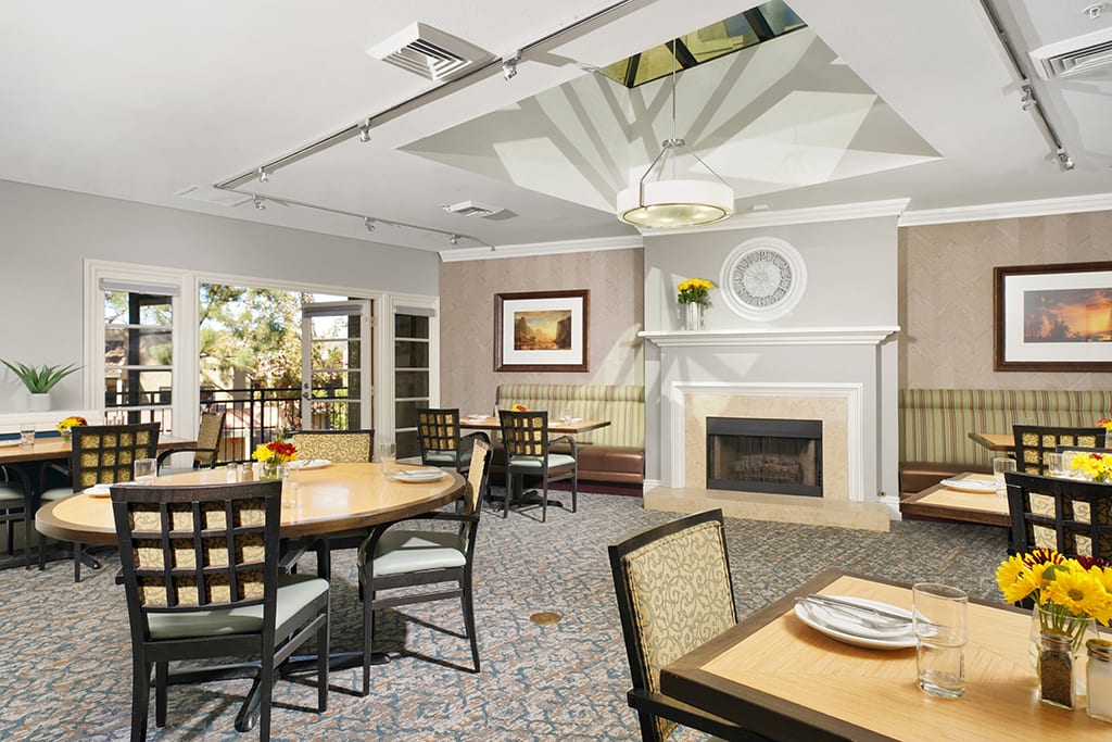 A modern dining room with elegant furniture, a fireplace, and tasteful artwork on the wall.