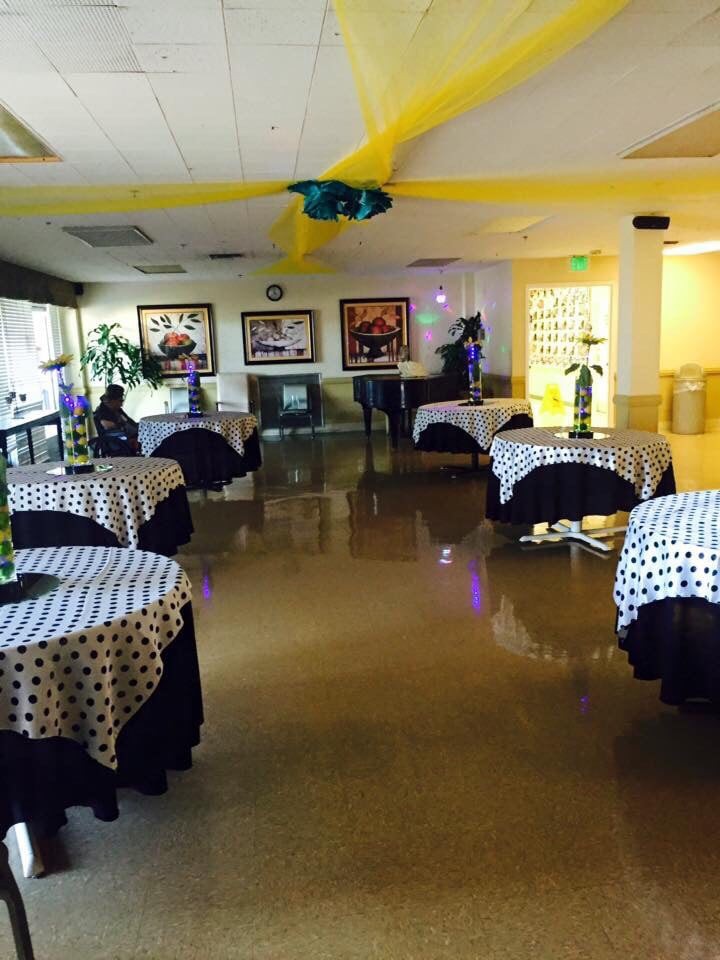 An indoor event space with decorated tables and balloons, prepared for a party or gathering.
