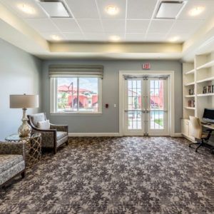 A cozy interior sitting area with comfortable chairs, a computer, and a large window letting in natural light.