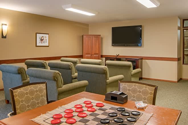 A cozy recreation room featuring a checkers board, comfortable seating, and a television.