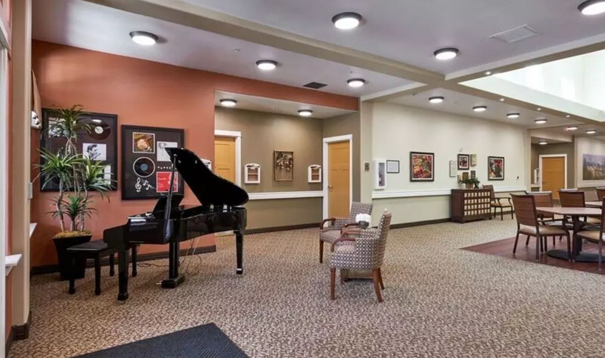 A cozy lobby area featuring a grand piano and comfortable seating, adorned with artwork on the walls.