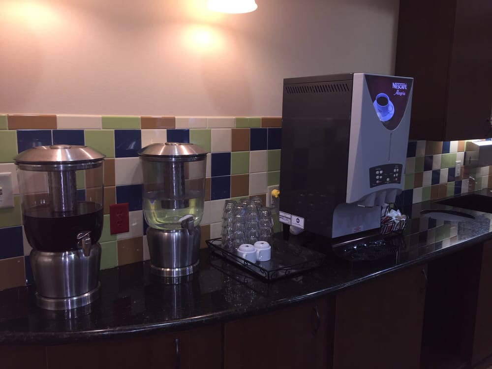 A self-service beverage station featuring juice dispensers and a coffee machine.