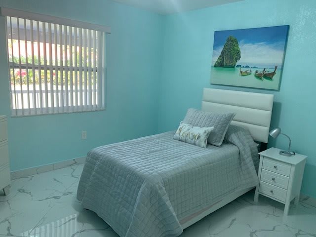 A cozy bedroom with turquoise walls, featuring a single bed and minimalist decor.