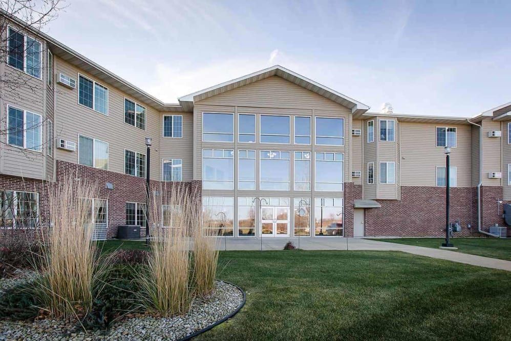 A modern residential building with large windows and a well-maintained lawn.