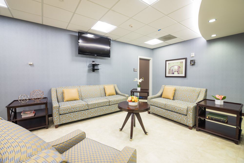 A modern waiting room with comfortable sofas and a television.