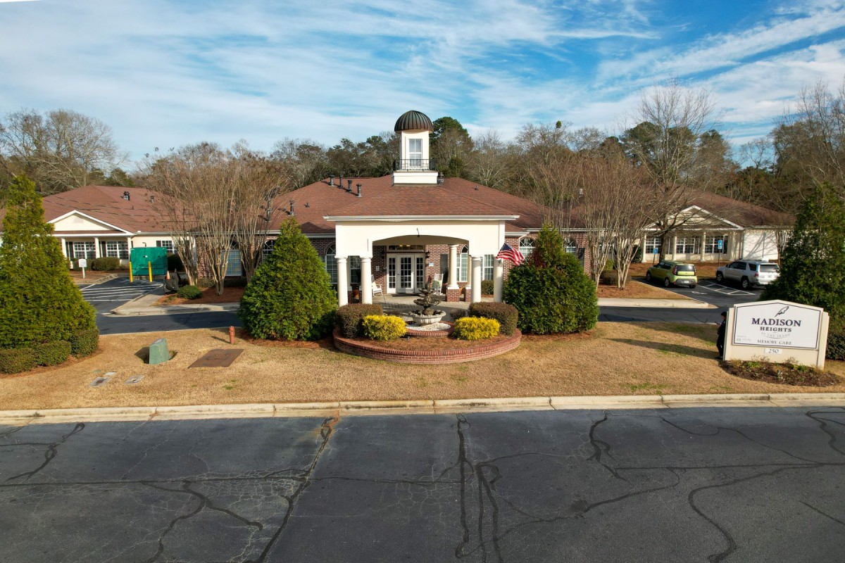 A picturesque building with a central fountain, surrounded by trees and a clear blue sky.