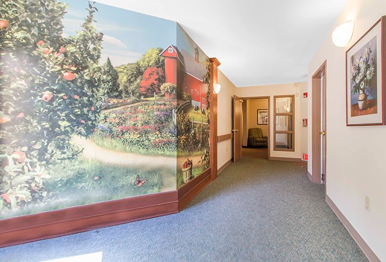 A hallway featuring a colorful mural depicting a scenic nature view with trees and a red barn.