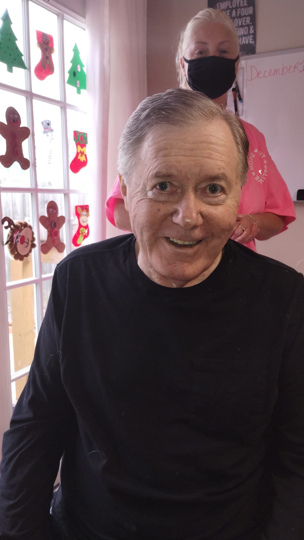 A smiling man indoors with holiday decorations in the background.