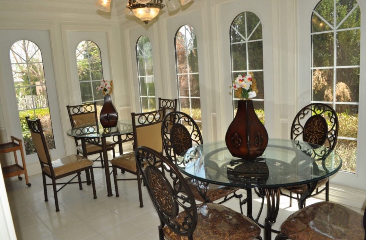 A bright dining area featuring glass tables, ornate chairs, and large windows allowing natural light to flood the space.