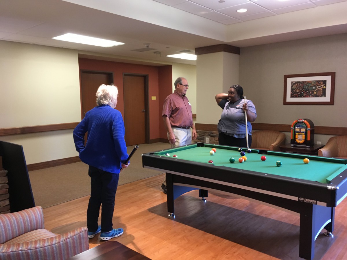 A group of people playing billiards in a community room.