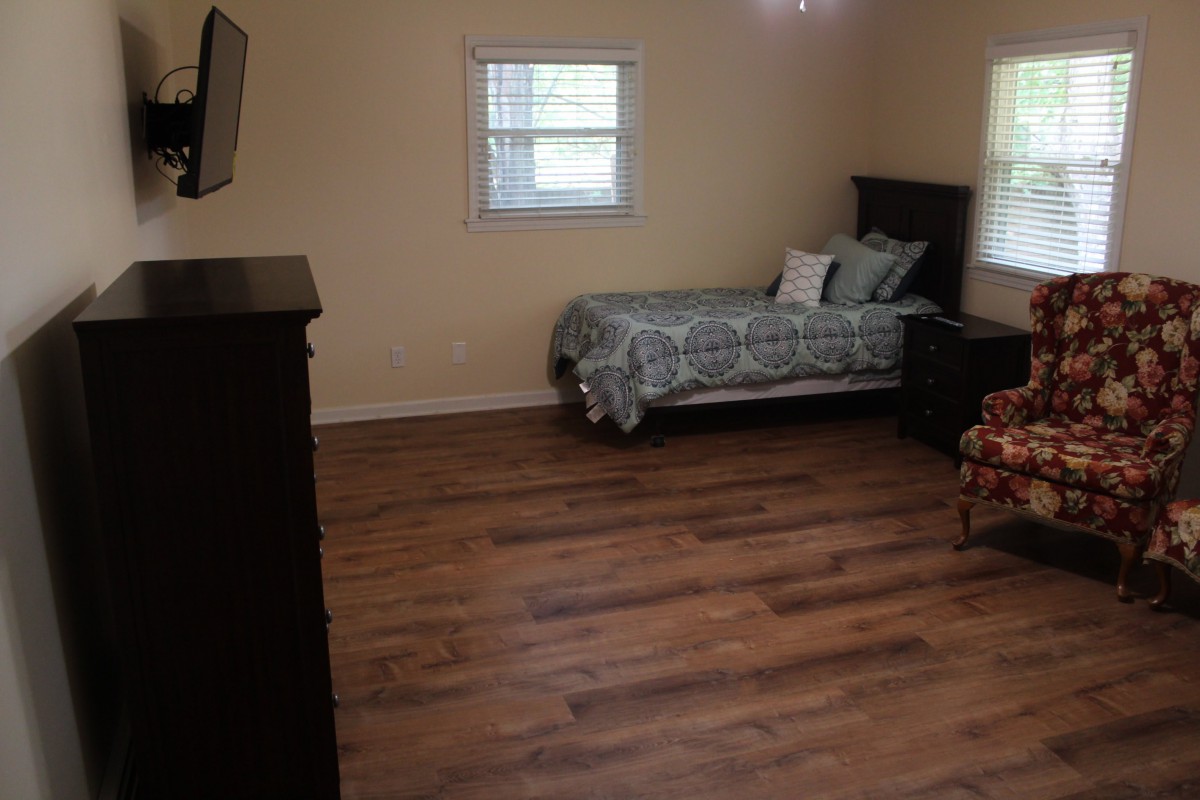 A minimalist bedroom with a single bed and wooden flooring.