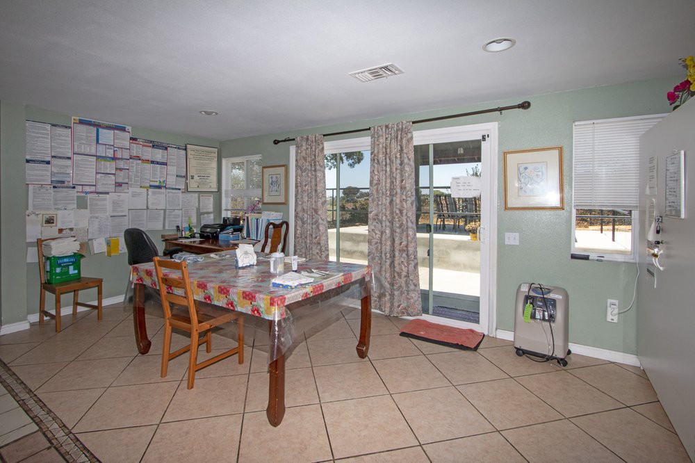 A cozy dining area with a table, chairs, and an office setup near sliding glass doors.