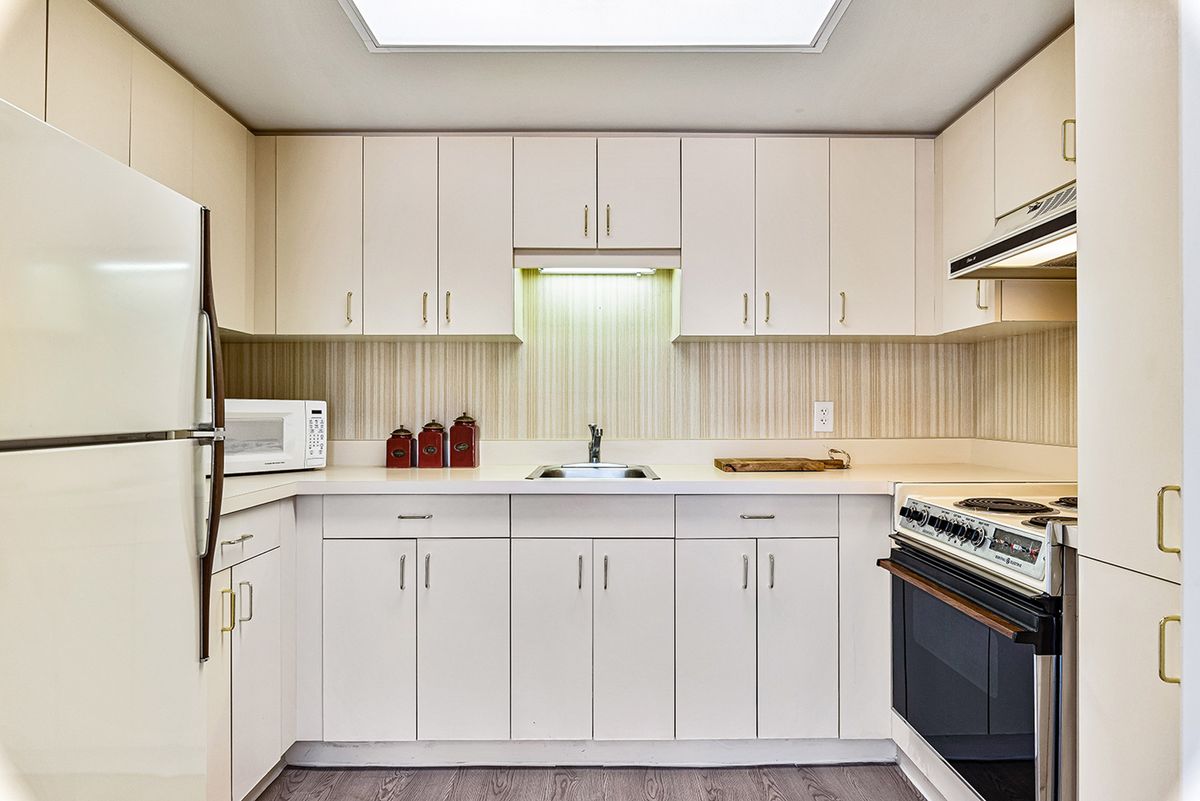 A modern kitchen interior with white cabinets and appliances.