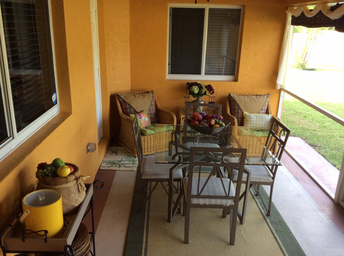 A cozy outdoor patio with a glass dining table and chairs, surrounded by comfortable seating and decorative plants.
