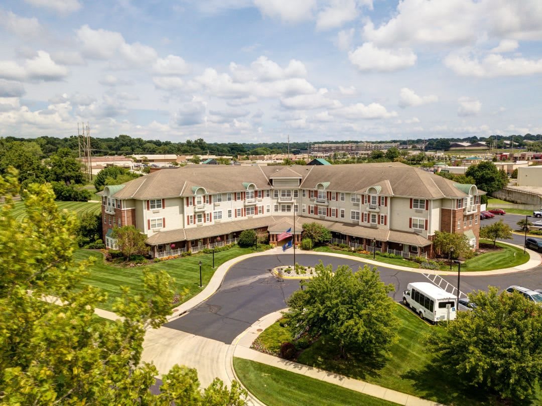 Aerial view of a large building surrounded by greenery and parking areas.