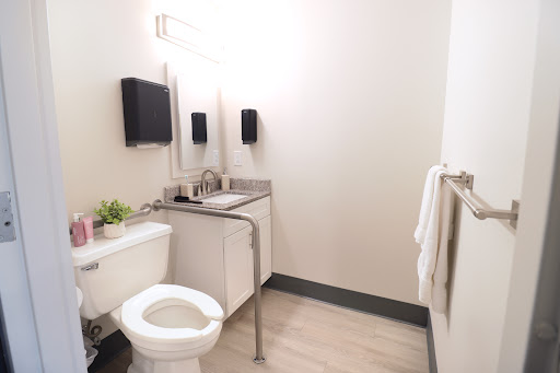 A modern and minimalist bathroom featuring a sink, toilet, and mirrors.
