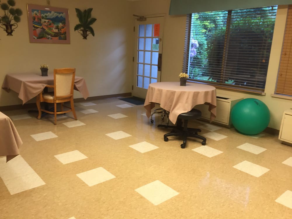 A cozy room with tables, chairs, and an exercise ball near a window.