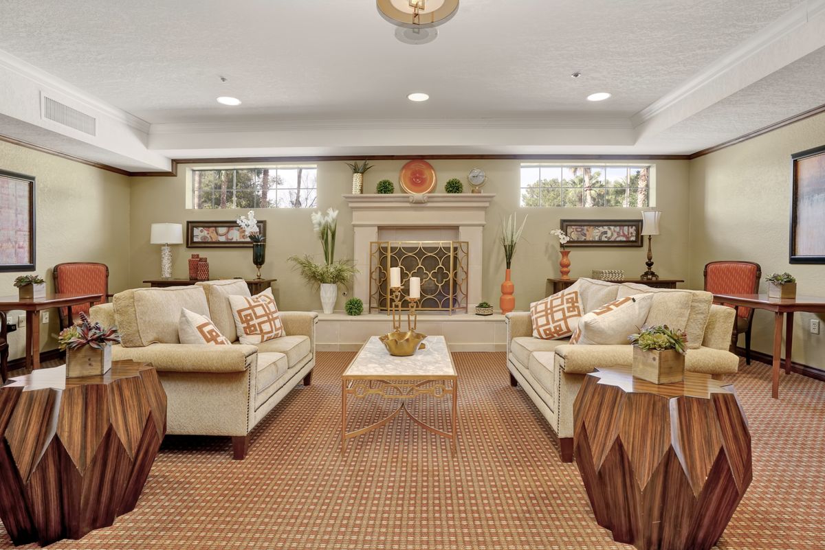 A cozy and elegantly decorated living room featuring two sofas, a coffee table, and a central fireplace.
