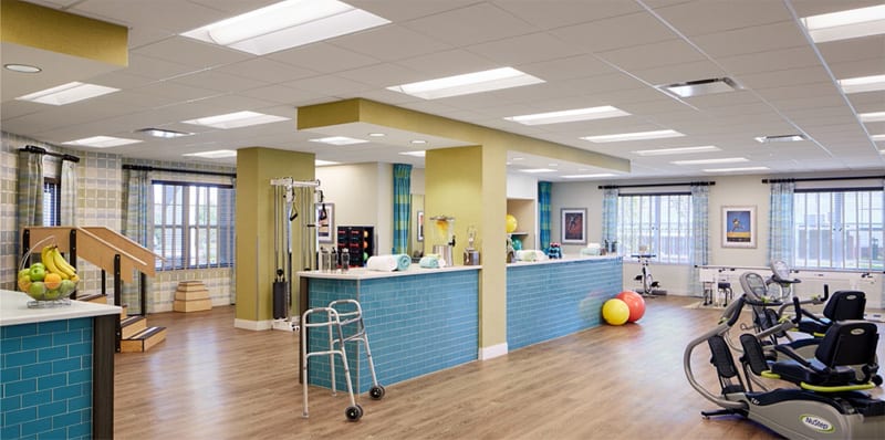 A well-equipped physical therapy and rehabilitation center with exercise equipment, a walker, and therapy balls.