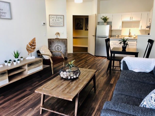 A modern and cozy living room with a connected kitchen and dining area, featuring wooden furniture and stylish decor.