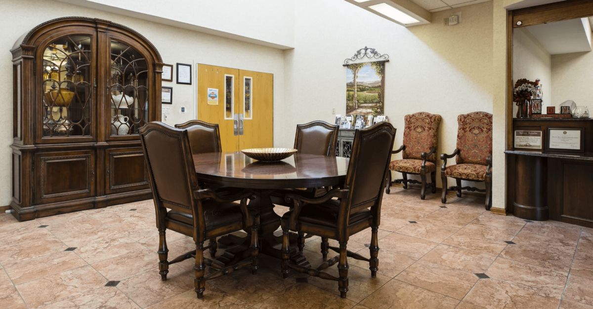 A dining area with a round wooden table surrounded by chairs, featuring elegant decor and a warm atmosphere.