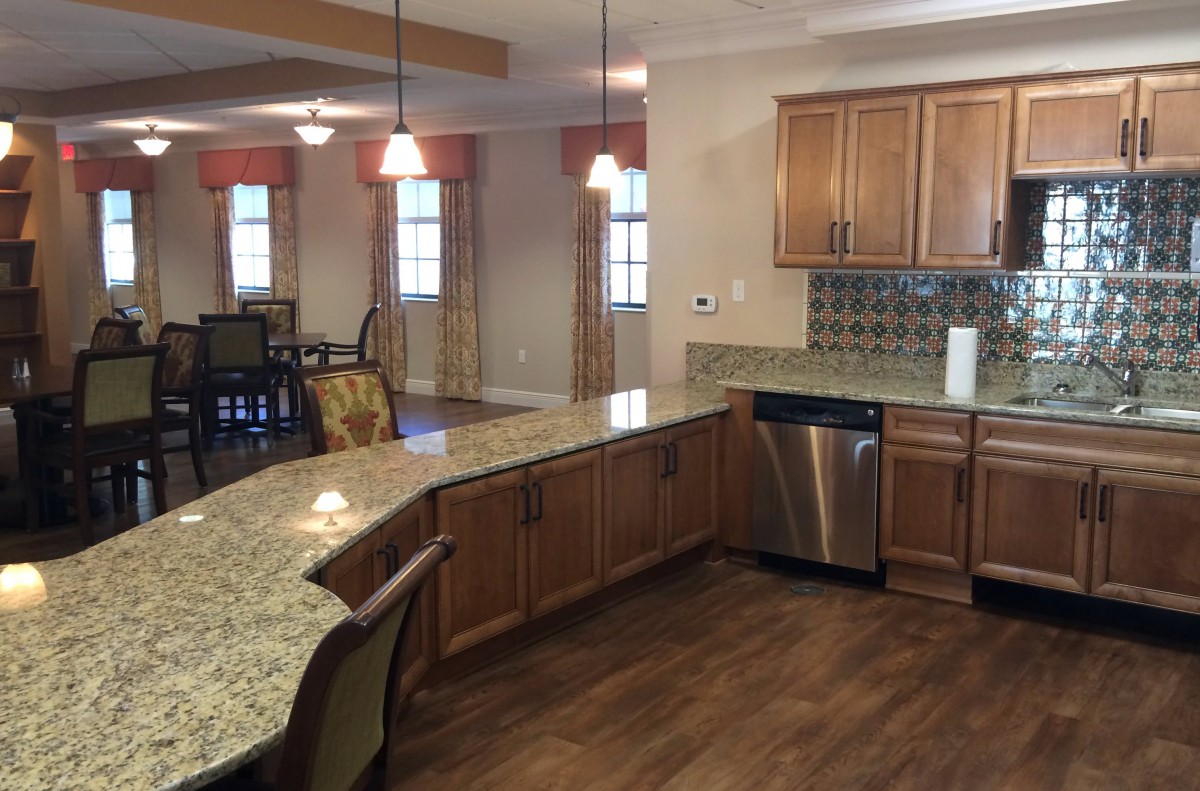A spacious kitchen with granite countertops and wooden cabinets opens into a dining area.