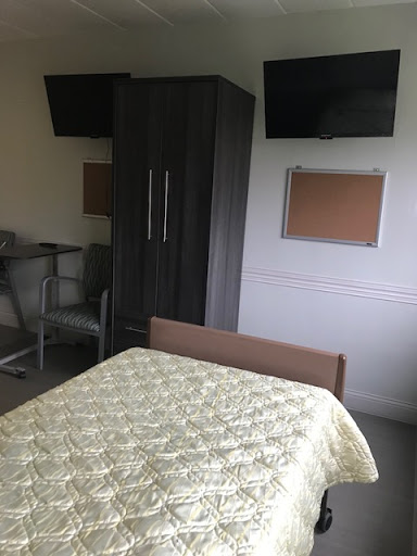 A simple and functional room featuring a bed, wardrobe, and workspace.