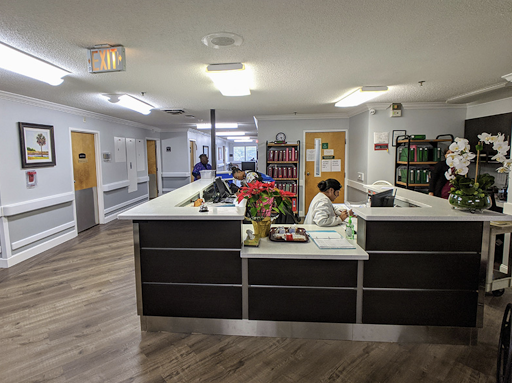 A view of the reception area in a healthcare facility, featuring a desk and staff attending to visitors.