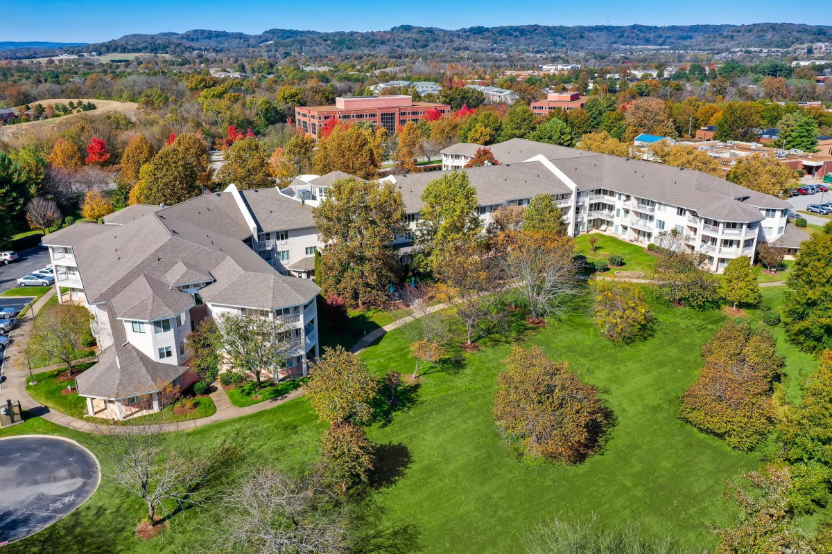 Aerial view of a large residential building surrounded by lush greenery and trees.