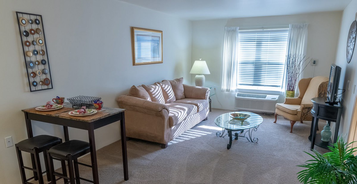 A cozy living room with a sofa, coffee table, and a lamp near the window.