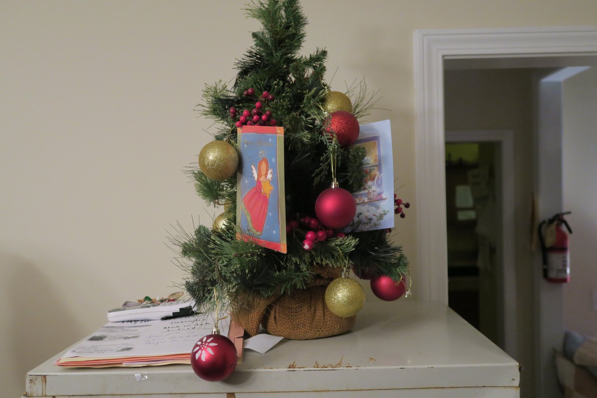 A small Christmas tree adorned with colorful ornaments and holiday cards.