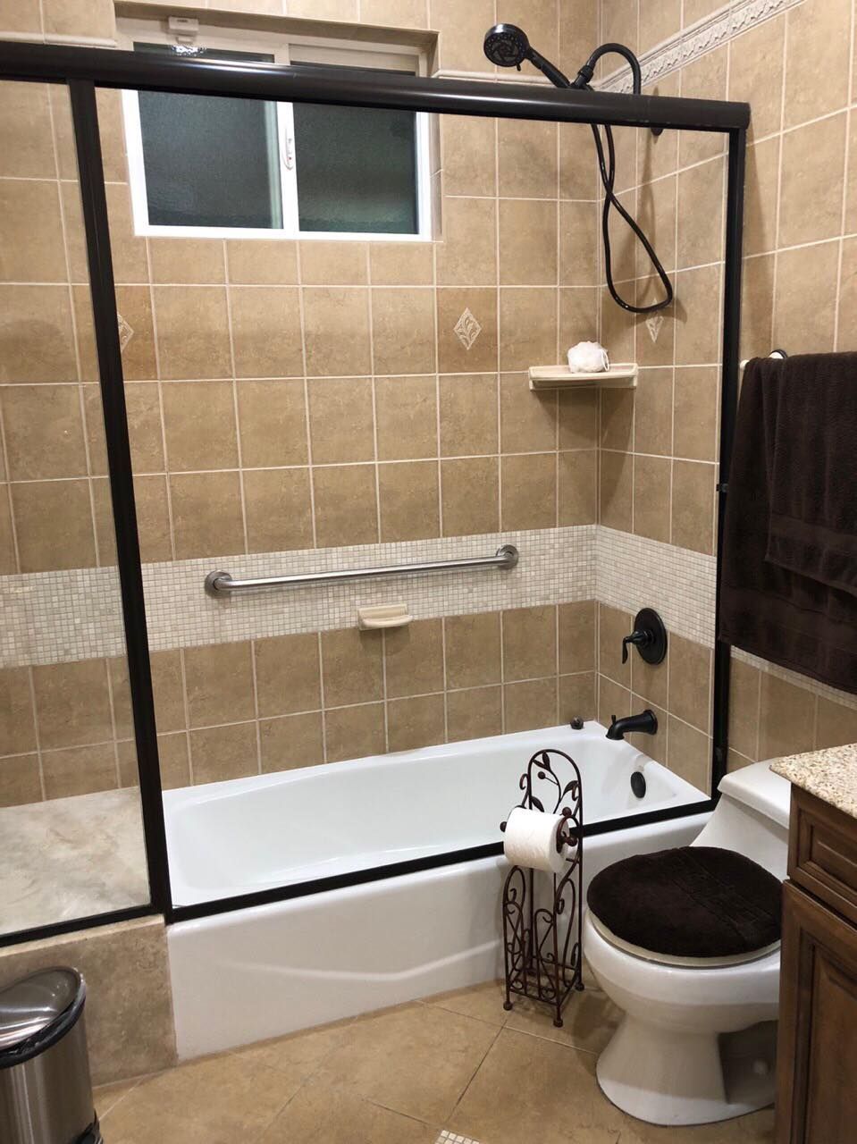 A modern bathroom with a tiled shower and bathtub area, featuring a glass door and mounted towel rack.