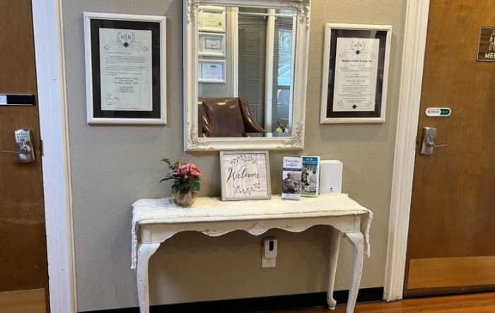 A stylish interior featuring a white console table with decorative items, a mirror, and framed certificates on the wall.