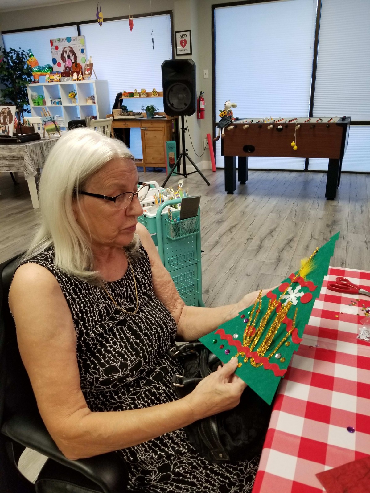 A woman holding a handcrafted Christmas tree decoration indoors.