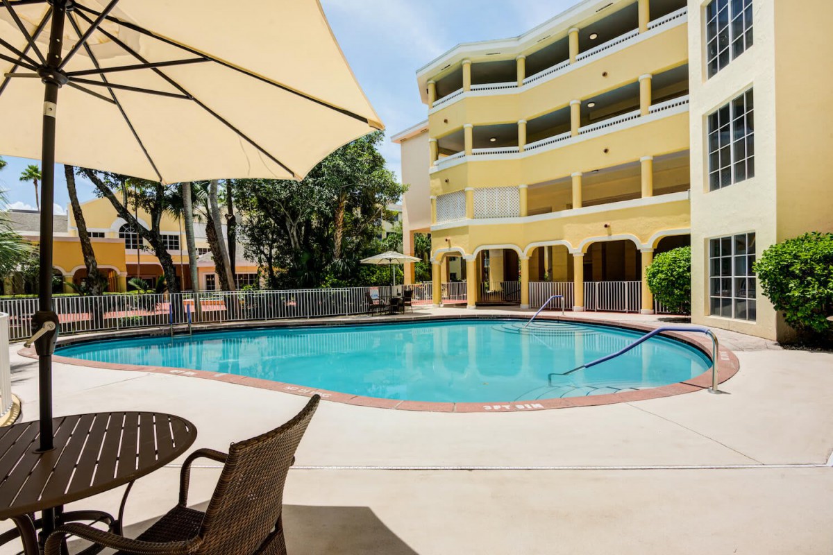 A sunny day at a hotel with an inviting swimming pool and patio seating.