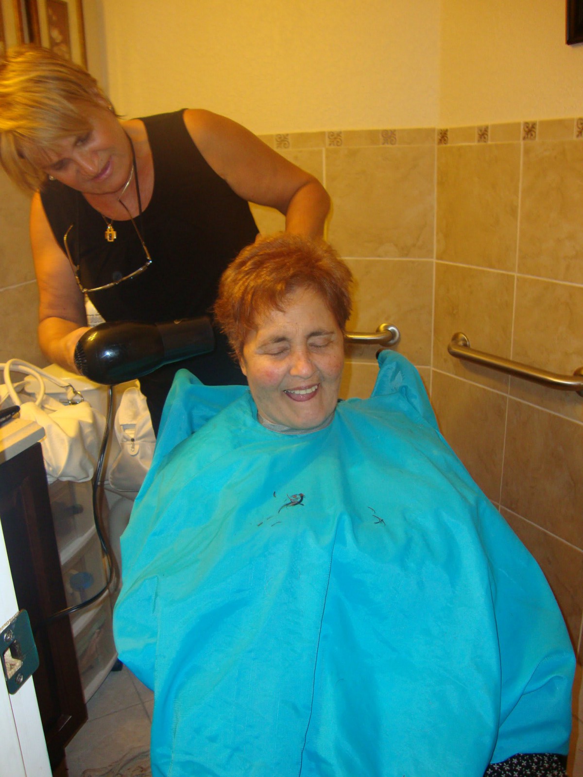 A person enjoying a haircut at the salon with a hairdresser.
