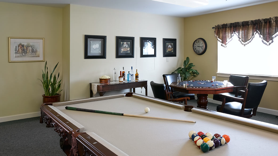 A stylish games room featuring a pool table, bar area, and wall decor.