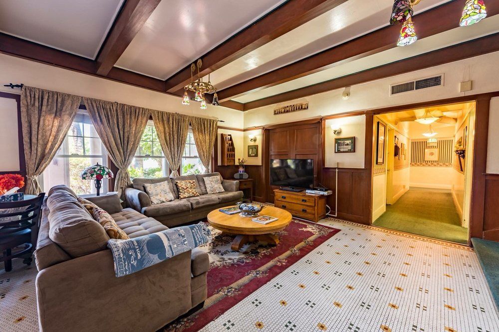 A cozy living room with traditional decor, featuring wood beams, a comfortable sofa, and a classic rug.
