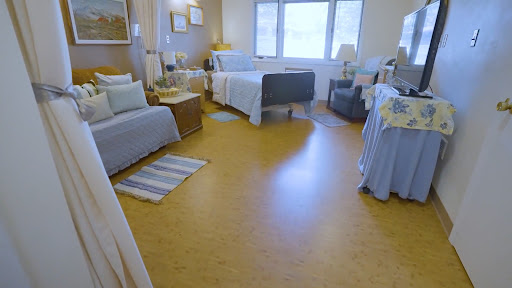 A well-lit hospital patient room featuring a bed, chair, and personal touches for comfort.