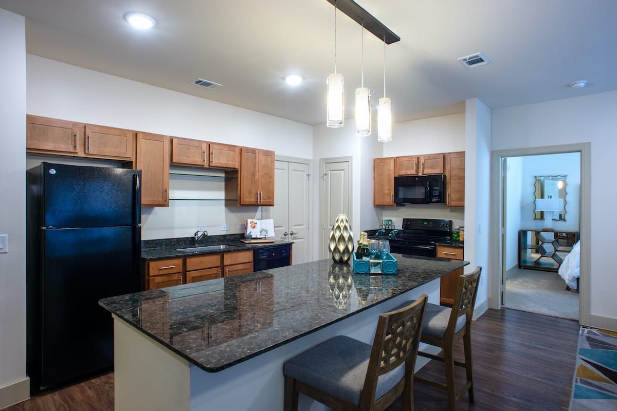 A modern kitchen with wooden cabinets, a granite countertop, and barstools.