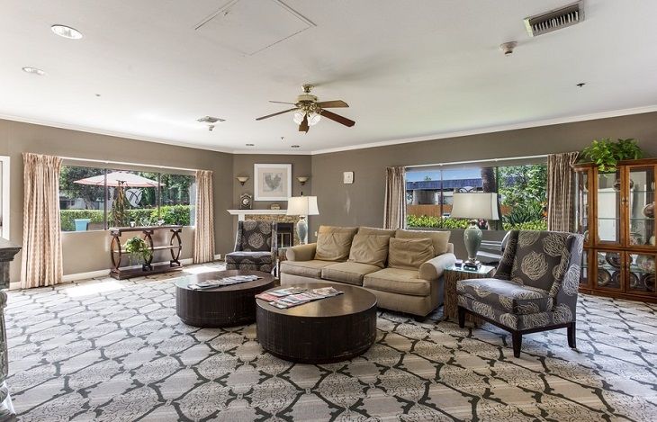 A cozy living room with a comfortable sofa, coffee tables, and large windows offering natural light.
