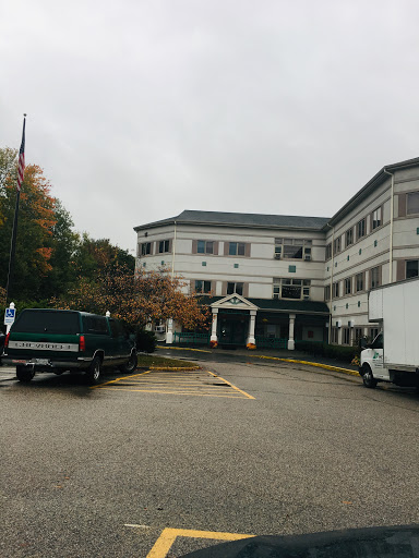 A commercial building with vehicles parked in front under a cloudy sky.