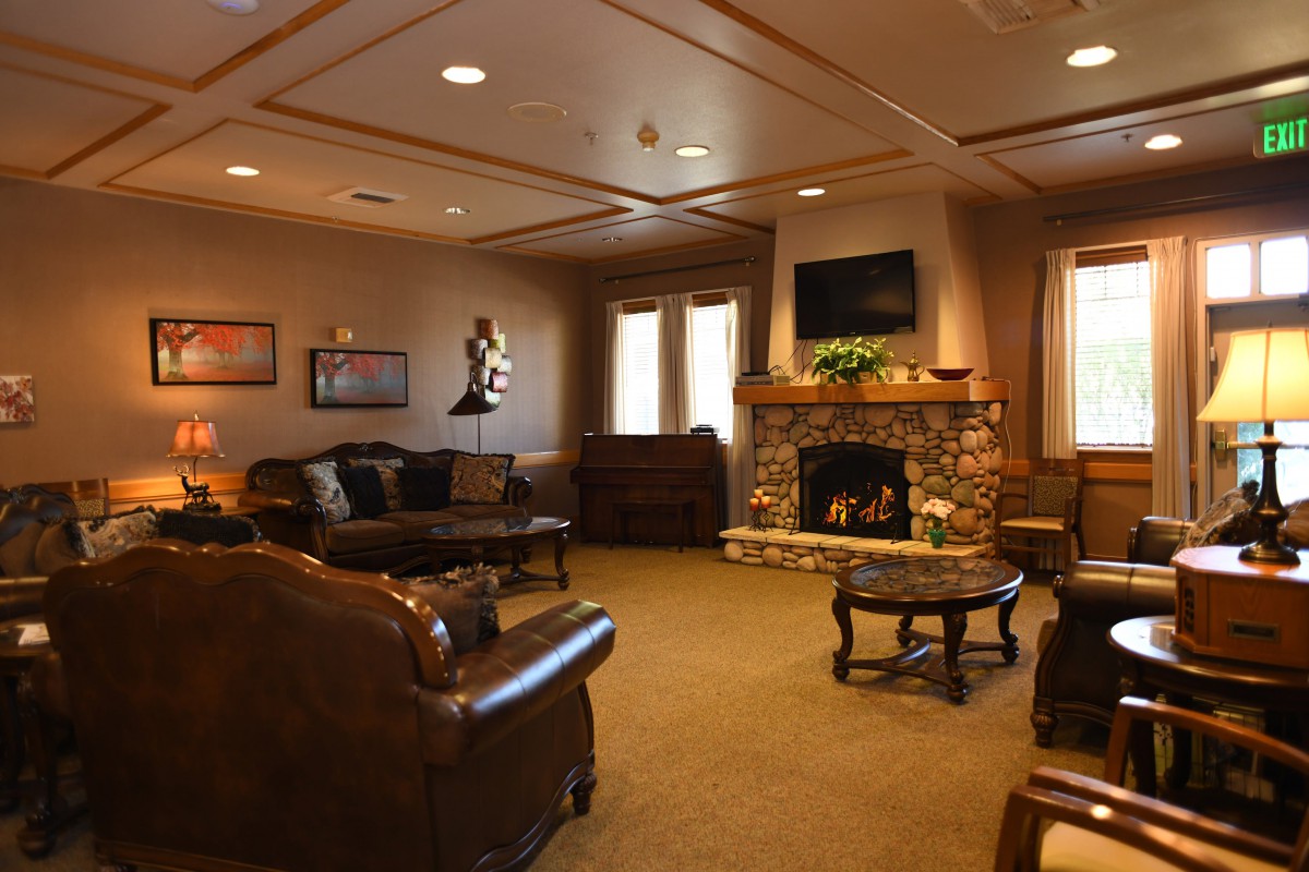 A cozy living room featuring a stone fireplace, leather sofas, and a wall-mounted television.