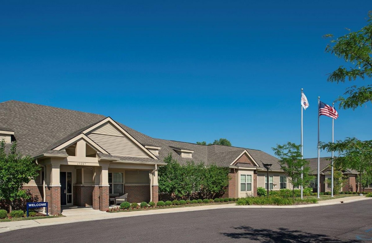 A suburban residential building with a garden and flagpole on a clear day.