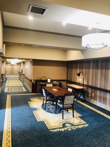 A hotel lobby area with a table, chairs, and elegant carpeted hallway.