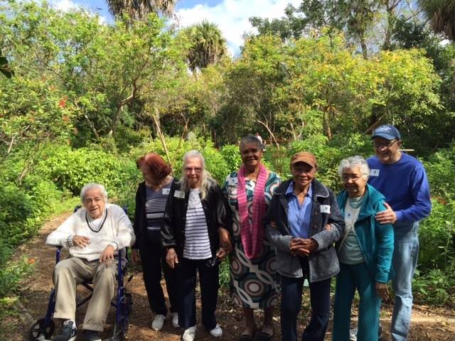 A group of people posing together in a lush garden setting.
