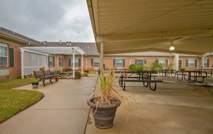 A covered patio area with tables and benches in a courtyard setting.