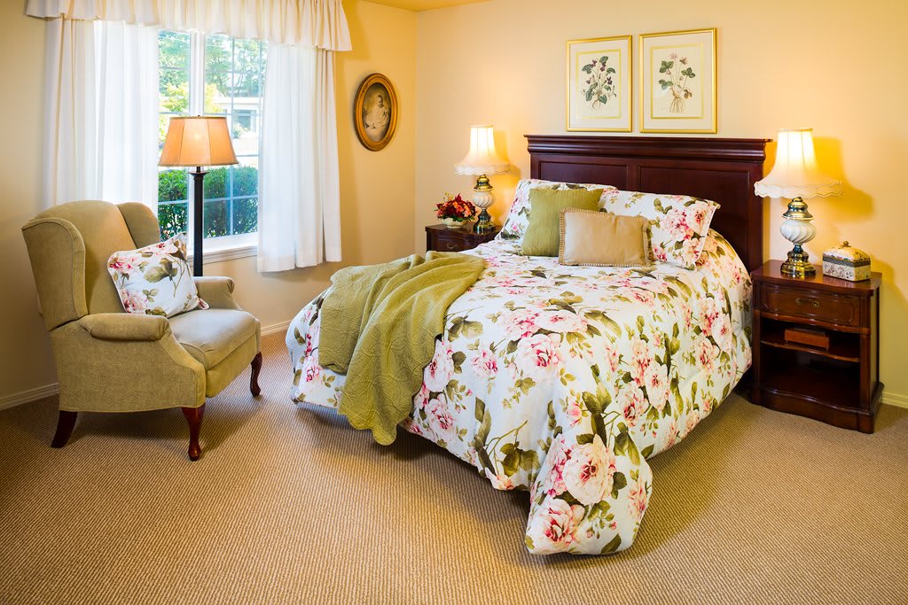 A cozy bedroom with floral bedding and traditional decor.