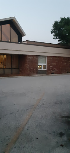 An exterior view of a brick building featuring a large window, taken during the evening.