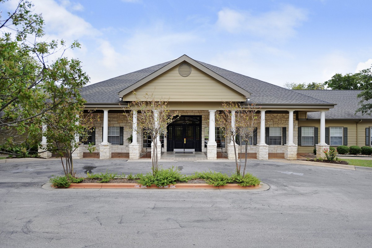 A single-story building with a prominent entrance and surrounding columns, set against a clear sky.
